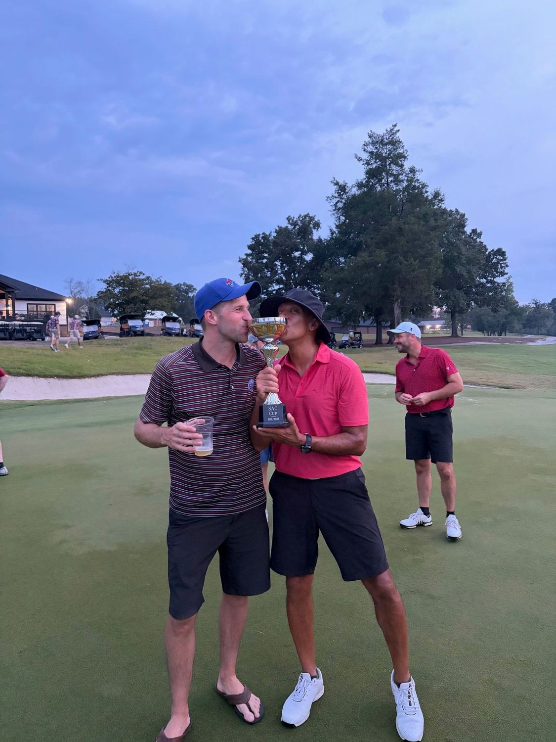 A competitor kissing the SAC Cup trophy on the 18th green