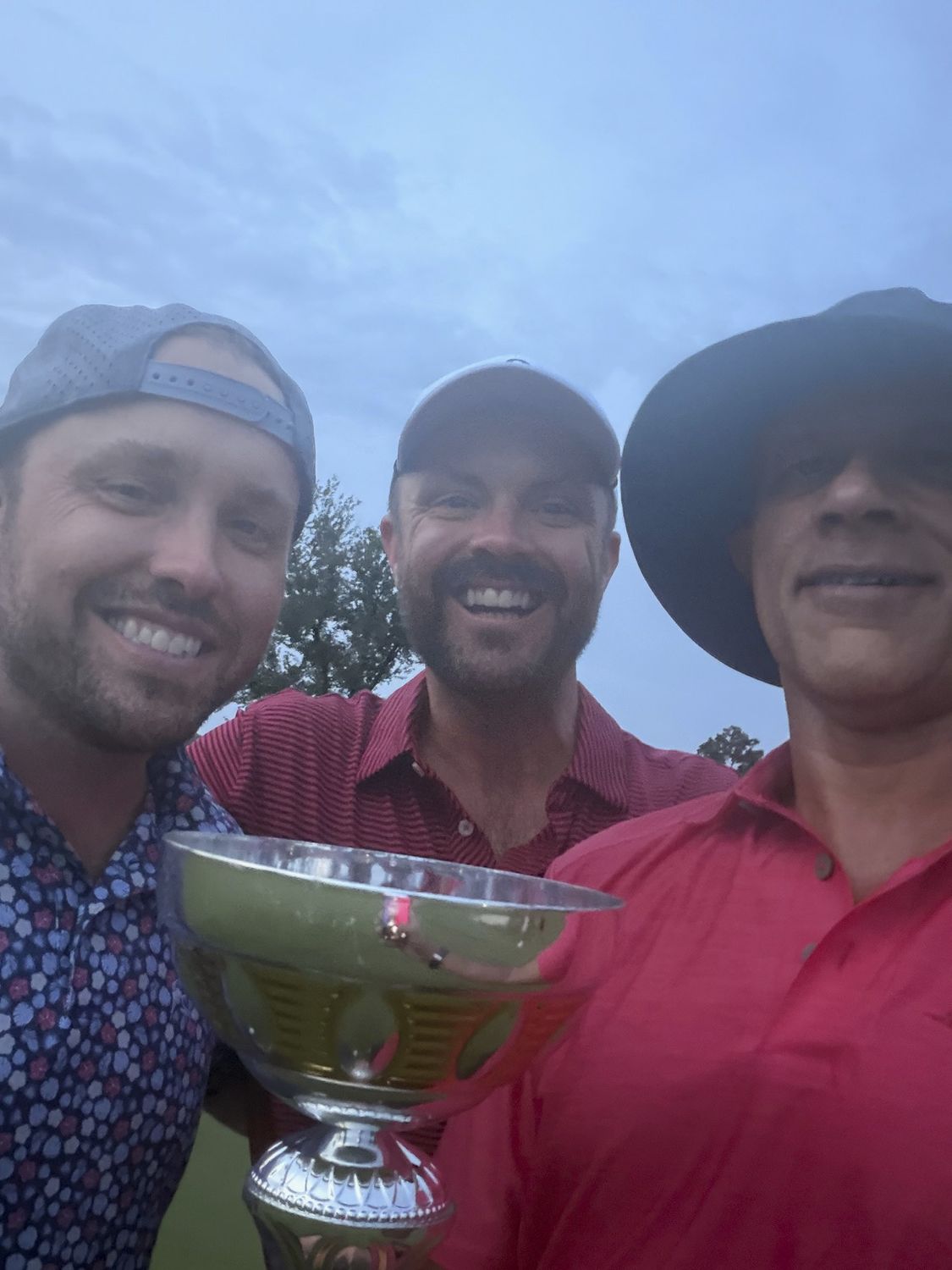 Three competitors crowded around the SAC Cup trophy at dusk