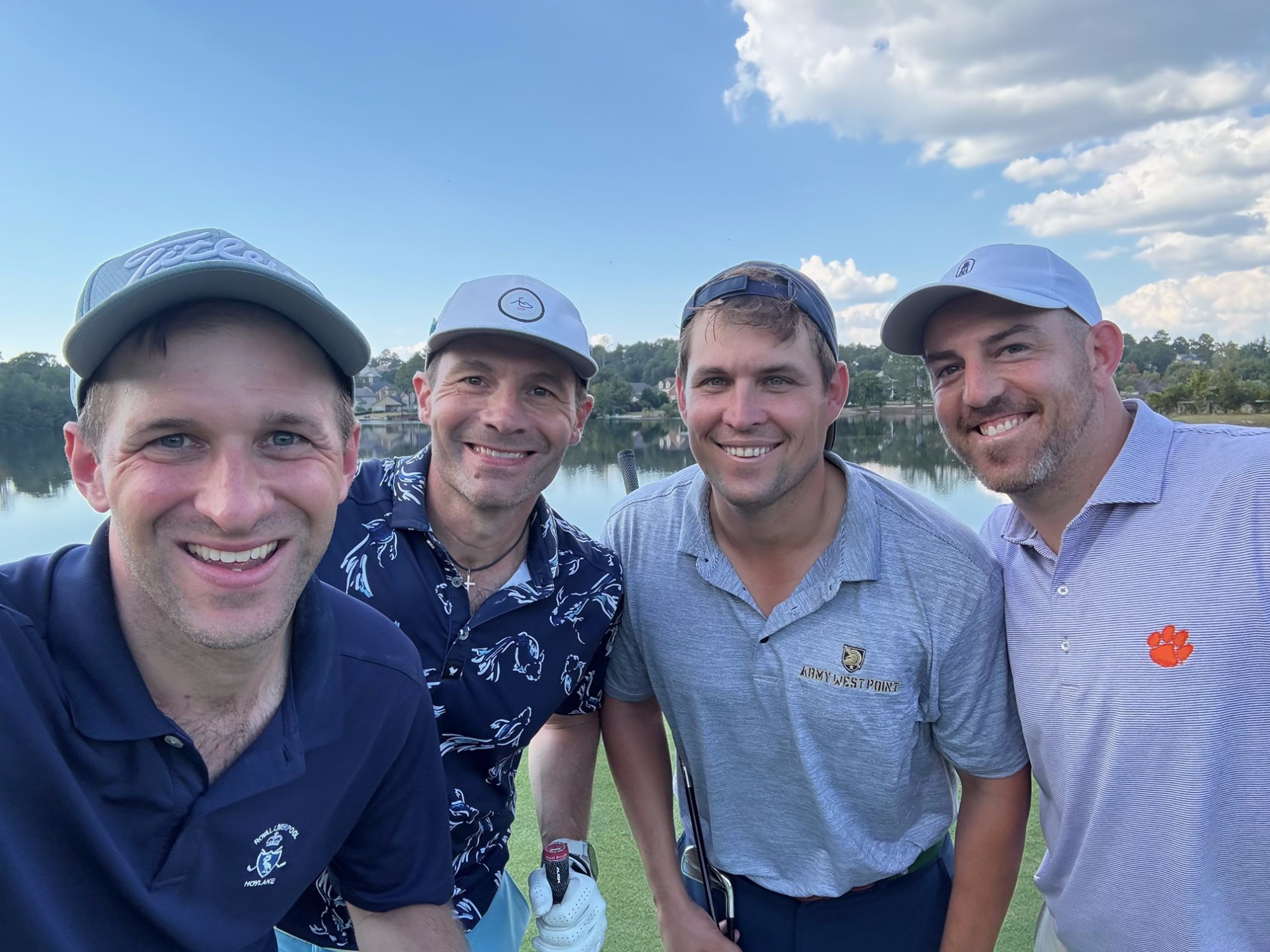 Foursome selfie on the course with lake backdrop